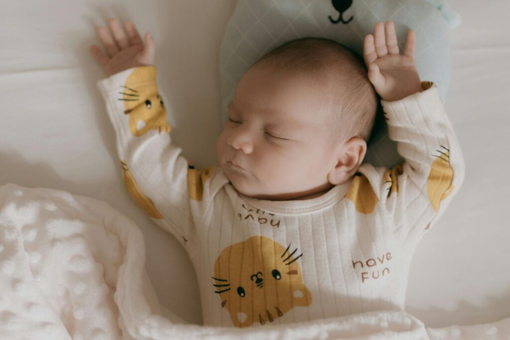 Un bébé dort paisiblement avec les bras en l'air