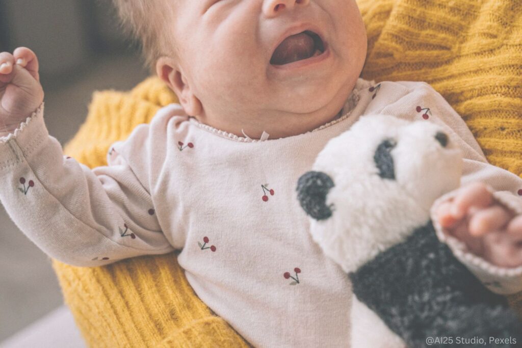 Photo d'u bébé qui pleure et s'agite dans les bras d'un adulte
